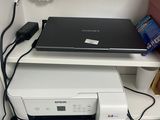 a laptop sitting on top of a printer on a desk