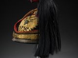 a black and gold hat with long black hair on a stand