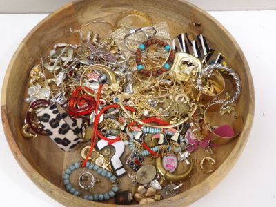 un bol en bois rempli de bijoux divers, posé sur une table