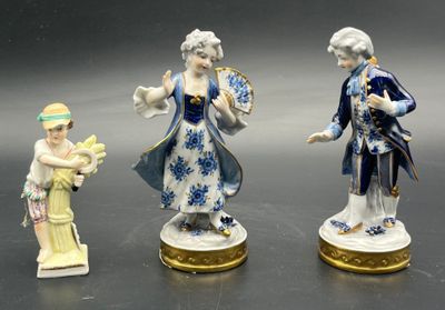 three figurines of people standing next to each other on a table