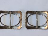 pair of silver buckles on a white surface