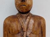 wooden figurine of a man with a cross on his chest