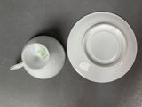 a cup and saucer sitting on a table next to each other