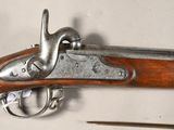 a close up of a gun on a white surface with a pair of scissors