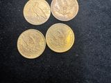 four different types of gold coins on a black surface