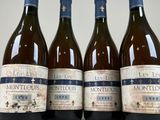 four bottles of wine are lined up on a white surface