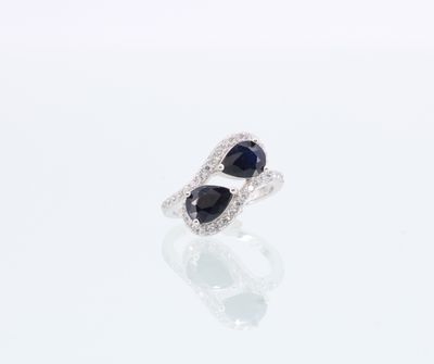 une image représentant une paire de bagues en saphir et diamant posées sur une surface blanche