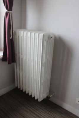 a radiator in the corner of a room next to a window
