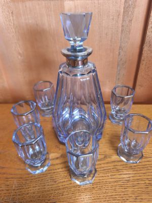 une carafe en verre et des verres à shot posés sur une table