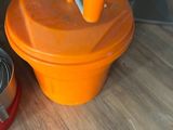 un récipient orange posé à côté d'un saladier en métal, par terre