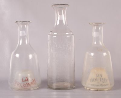 trois bouteilles en verre munies d'étiquettes, posées sur une table