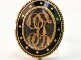une image représentant une bague dorée et noire ornée d'un monogramme