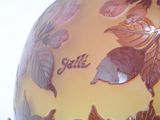 a yellow vase with brown leaves on it and a name written on it