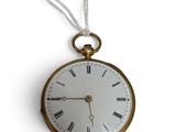 une montre à gousset en or suspendue à un mur blanc