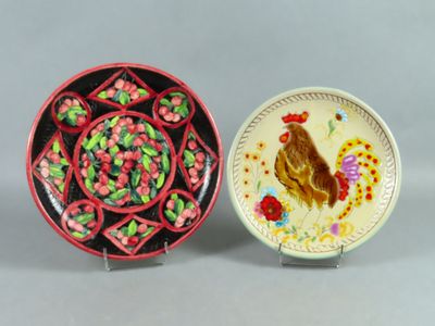 two plates with designs of roosters and flowers on them