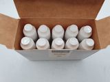 six bouteilles contenant un liquide blanc, rangées dans une boîte posée sur une table