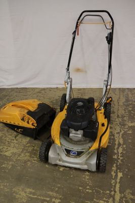 une tondeuse à gazon jaune et noire à côté d'un sac jaune et noir