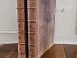 two old books sitting on a wooden table in a room