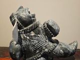 a statue of a teddy bear holding a piece of paper on a table