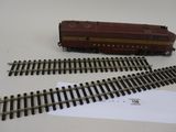 un petit train sur les rails, à côté d'une feuille de papier