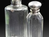 two clear glass bottles with silver lids on a black surface
