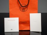 an orange paper bag with a brown handle sitting on top of a table