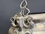 a large metal vase with a knot hanging from it ' s side