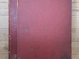 an old red book sitting on top of a wooden table