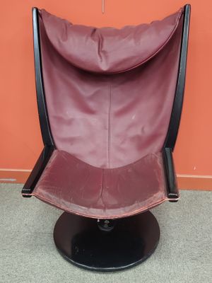 fauteuil en cuir violet devant un mur orange, avec un piètement noir