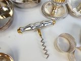 de nombreux objets en argent posés sur une table, avec un décapsuleur