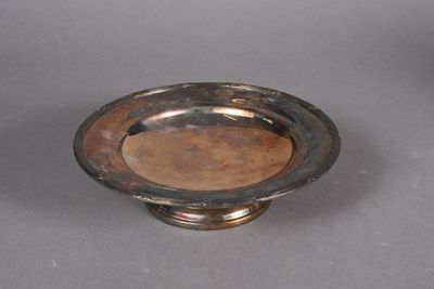 an antique silver plate on a gray surface