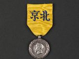 a close up of a medal on a black surface with a yellow ribbon