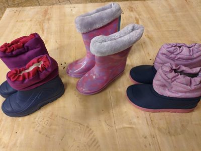 trois paires de bottes sont alignées sur une surface en bois