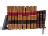 several old books are lined up in a row on a white surface