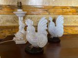 three white rooster figurines sitting on a table