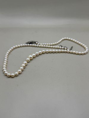 a close up of a white pearl necklace on a white surface