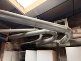 a metal pipe in the middle of a room with a skylight above it