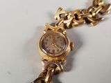 a gold watch with a chain around it on a white surface