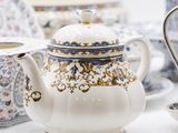 a white tea pot sitting on a table next to a cup and saucer
