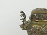 a bronze vase with a bird on it on a stand