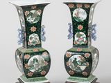 pair of green vases with floral designs on stands on a white background