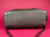 an image of a brown leather purse on a pink background
