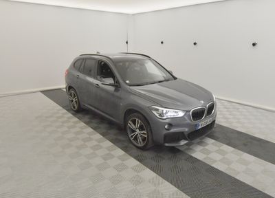 the bmw x1 is parked in a garage with a checkered floor