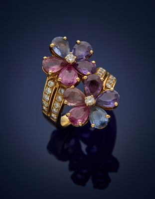 a close up of a gold ring with pink and blue sapphires