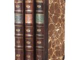 three old books sitting on top of each other on a white surface