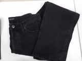 black jeans on a white table next to a book and a cell phone