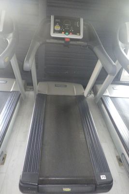 un tapis de course au milieu d'une pièce, avec un écran accroché au mur