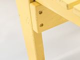underside view of a yellow wooden bench against a white background