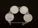 four silver coin bracelets on a black surface with a chain