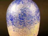 un vase bleu et jaune posé sur une surface noire